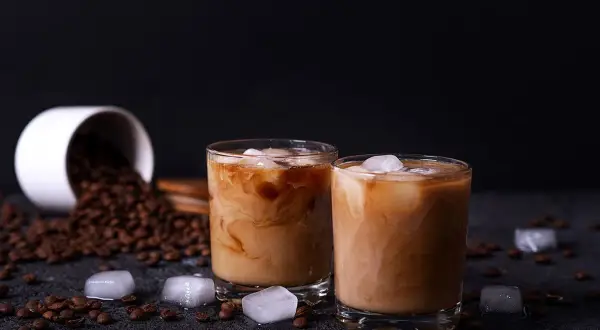 Due bicchieri di crema di caffè senza panna, con chicchi di caffè e cubetti di ghiaccio sparsi.