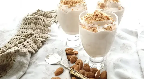Delizioso espressino freddo pugliese in bicchieri, guarnito con mandorle tritate. Accanto, mandorle intere e un cucchiaino.