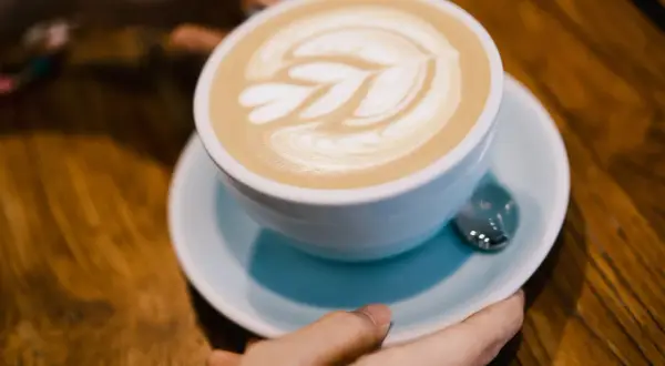 Un flat white con schiuma artistica, pronto per essere gustato su un tavolo di legno.
