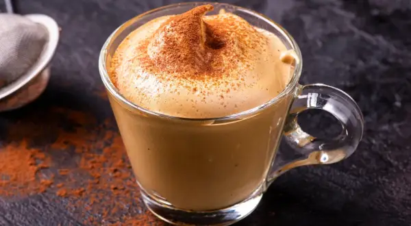Una tazza di crema di caffè fatta in casa, spolverata di cacao, su uno sfondo scuro.