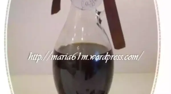 Caraffa di sciroppo al caffè fatto in casa, con etichetta scritta a mano e chicchi di caffè sparsi.