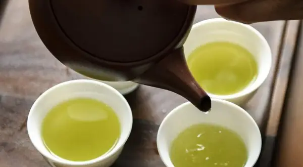 Versando tè verde in tazze. Quante tazze di tè verde bere al giorno? Un rituale rilassante.