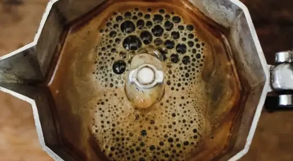 Caffè bollente nella moka, con bollicine che ricordano i sintomi dell'astinenza da caffeina.