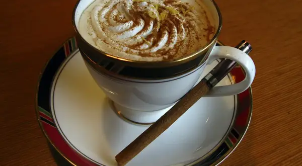 Caffè Pedrocchi ricetta: una tazza di caffè con panna montata, cannella e scorza di limone, accompagnata da un sigaro.
