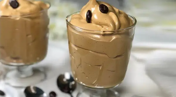 Deliziosa spuma di caffè in bicchieri, guarnita con chicchi di caffè. Perfetta per una pausa golosa.