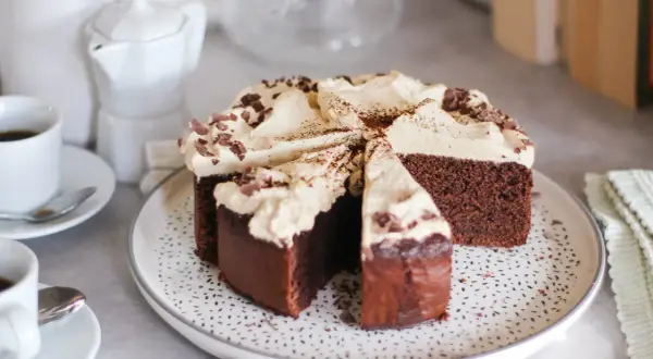 Una fetta di torta caffè e cioccolato, ricoperta di panna e scaglie di cioccolato, pronta per essere gustata con un caffè.
