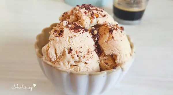 Coppetta di gelato al caffè, guarnita con scaglie di cioccolato e nocciole croccanti. Perfetto per una pausa golosa.
