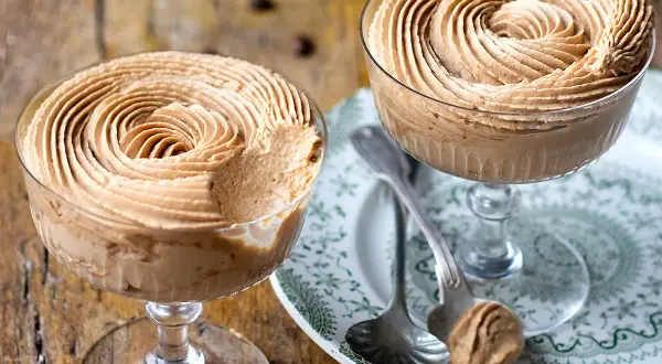 Due coppe di deliziosa mousse di caffè, guarnite a spirale, su un piatto decorato.
