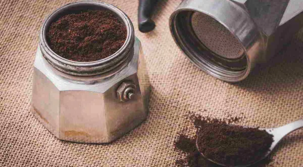 Il filtro moka incastrato è pronto per un caffè aromatico. Caffè macinato fine su tela di juta.