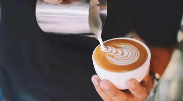 Latte art su un caffè, mostrando la differenza tra caffelatte e cappuccino con schiuma di latte versata.