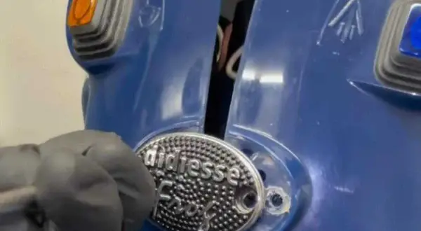 Dettaglio di una macchina del caffè blu, con un'etichetta "didiesse" e un guanto grigio che lavora su di essa.