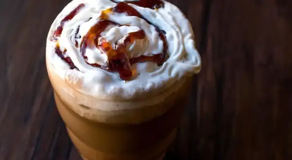 Frappuccino ricetta: un bicchiere di caffè freddo con panna montata e sciroppo caramello, perfetto per una pausa golosa.