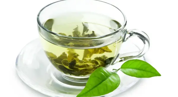 Tazza di tè verde con foglie infuse, un invito a scoprire i suoi benefici.