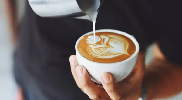 Un barista esperto crea un disegno latte art su un cappuccino, mostrando come fare il cappuccino perfetto.