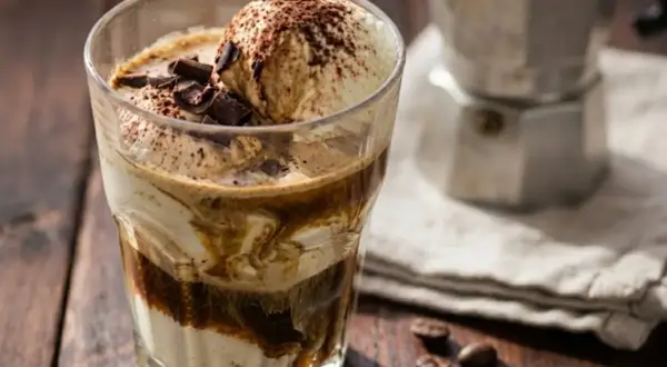 Un delizioso gelato affogato al caffè, guarnito con scaglie di cioccolato e cacao, pronto per essere gustato.
