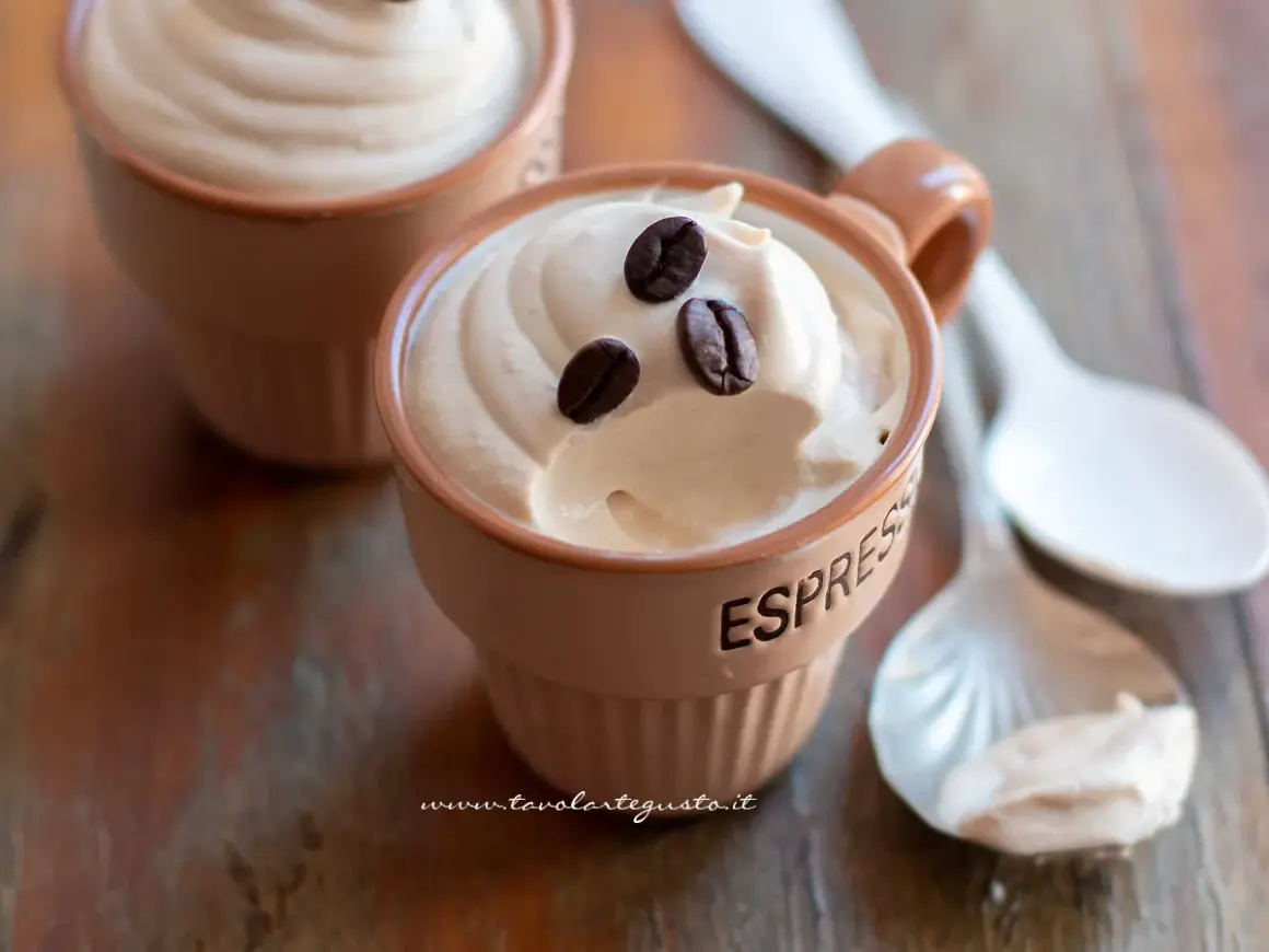 Deliziosa ricetta crema caffè con panna, guarnita con chicchi di caffè, servita in tazzine su un tavolo di legno.