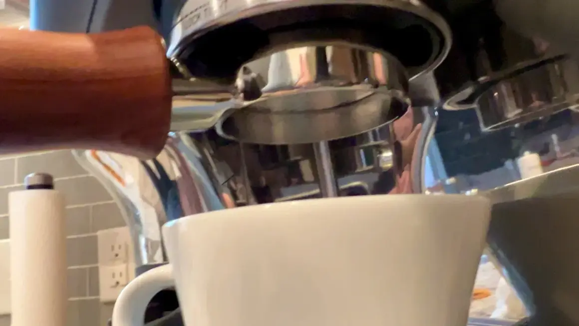 Manuale per capire come mettere le cialde nel portafiltro, con una tazzina bianca pronta a ricevere l'espresso.