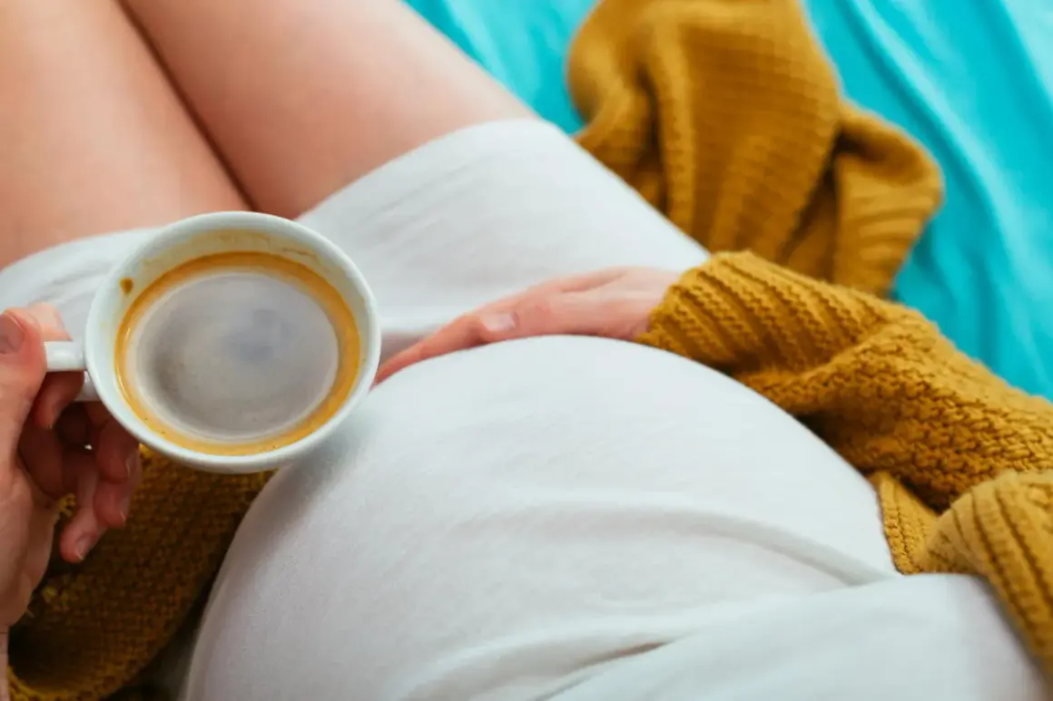 Mom-to-be enjoys a moment of peace with a cappuccino, resting her hand on her belly.
