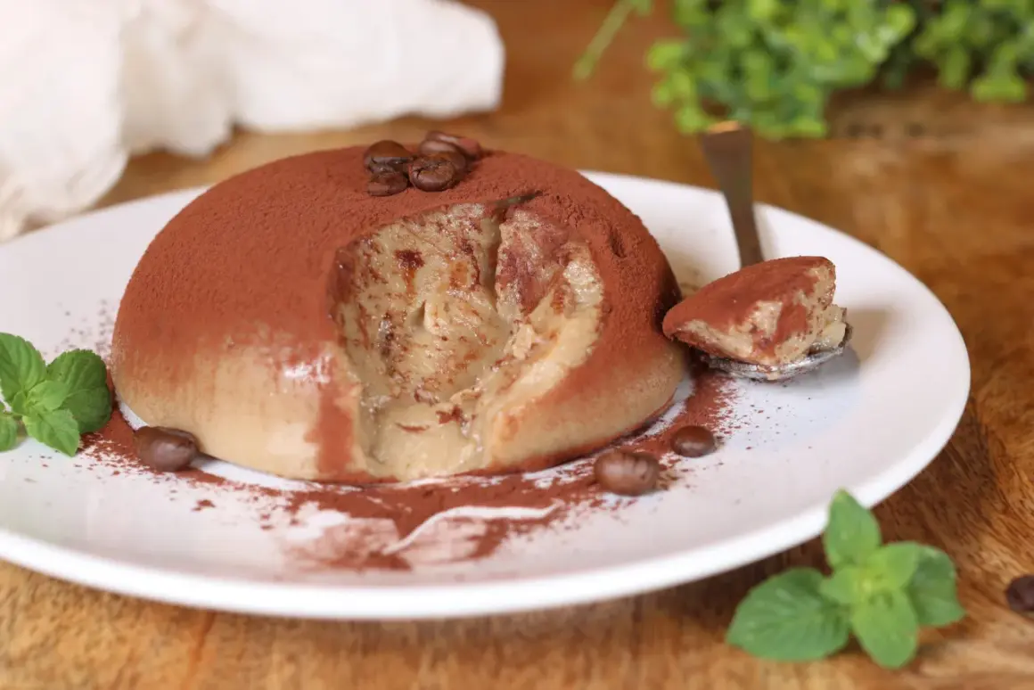 Delizioso budino al caffè, cosparso di cacao e chicchi di caffè, con una fogliolina di menta fresca.