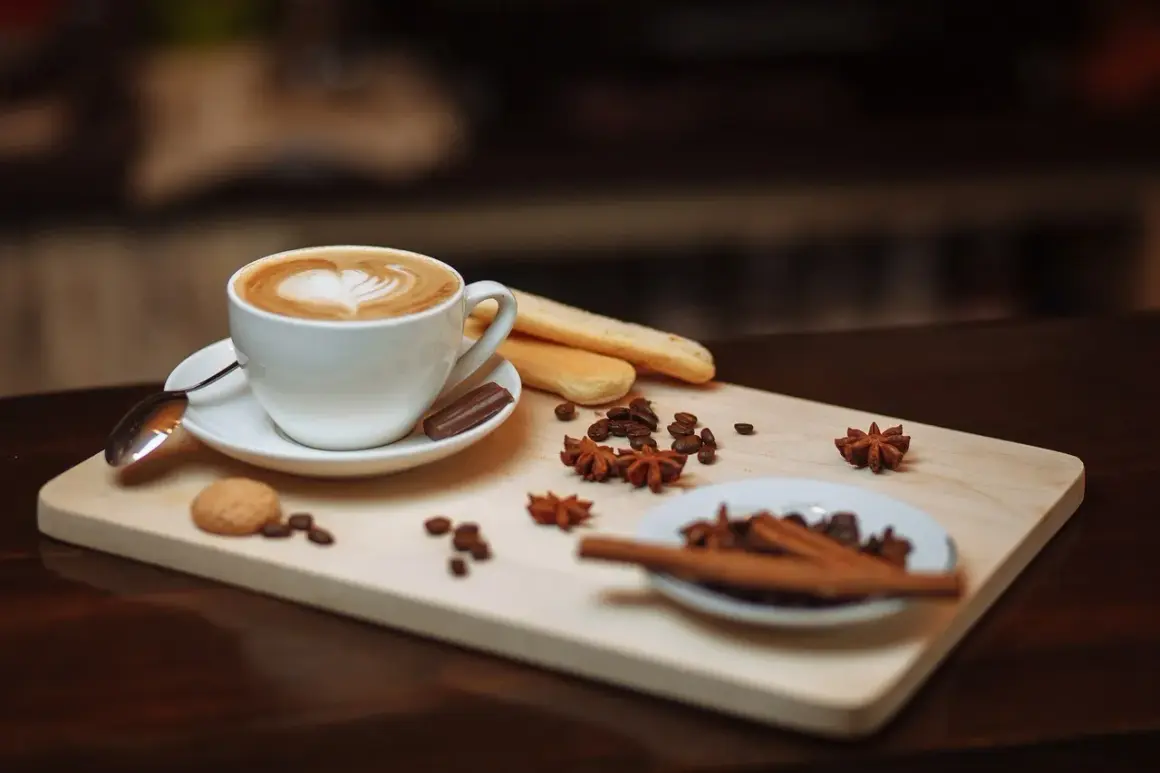 Un delizioso caffè fatto in casa con schiuma a forma di cuore, biscotti, chicchi di caffè e spezie su un tagliere di legno.