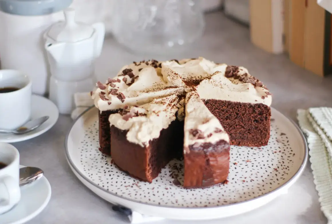 Una fetta di torta caffè e cioccolato, ricoperta di panna e scaglie di cioccolato, pronta per essere gustata con un caffè.
