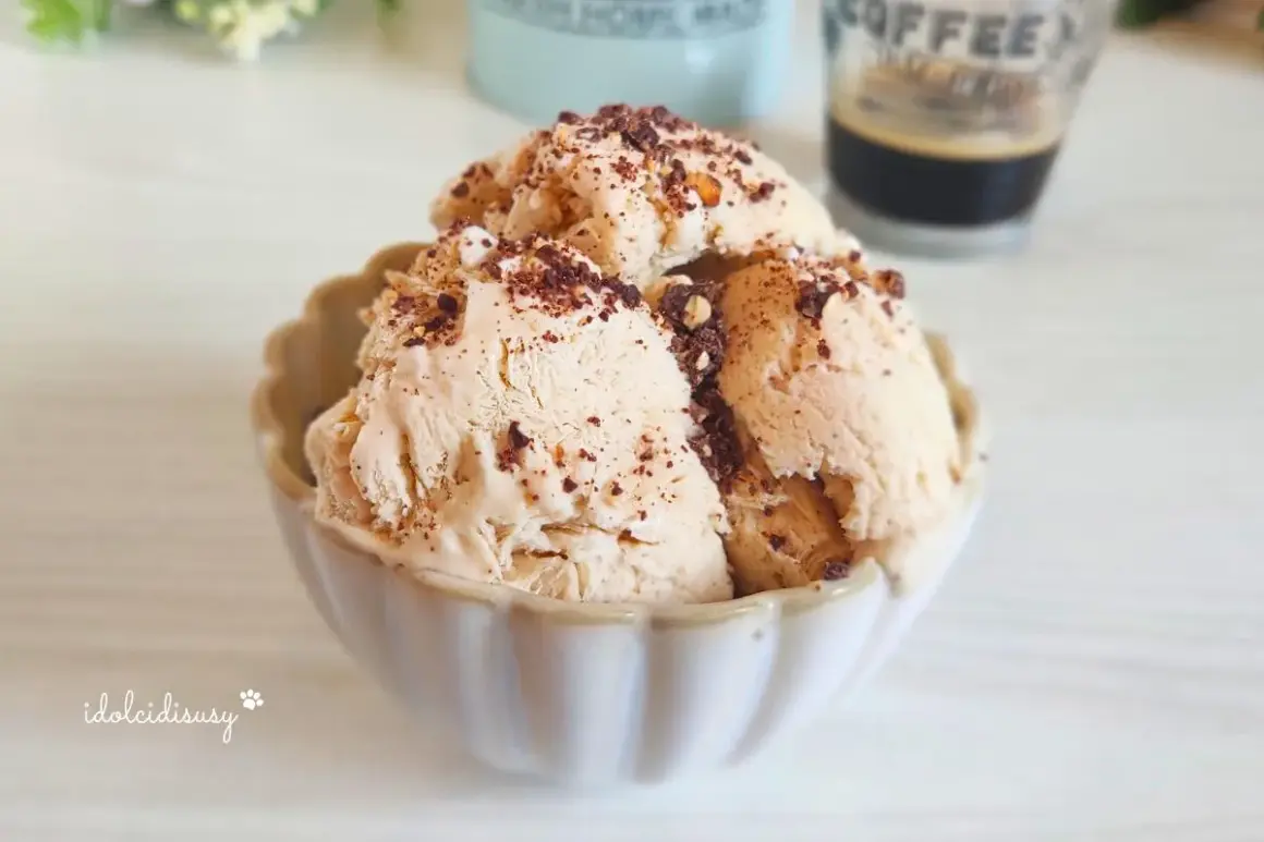 Coppetta di gelato al caffè, guarnita con scaglie di cioccolato e nocciole croccanti. Perfetto per una pausa golosa.