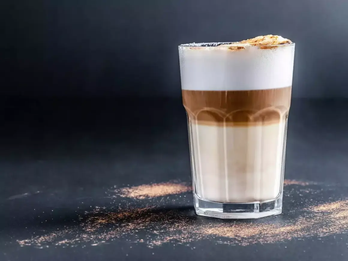Un bicchiere di latte macchiato con strati distinti di latte, caffè e schiuma. Ecco come si fa, un piacere visivo e gustativo.