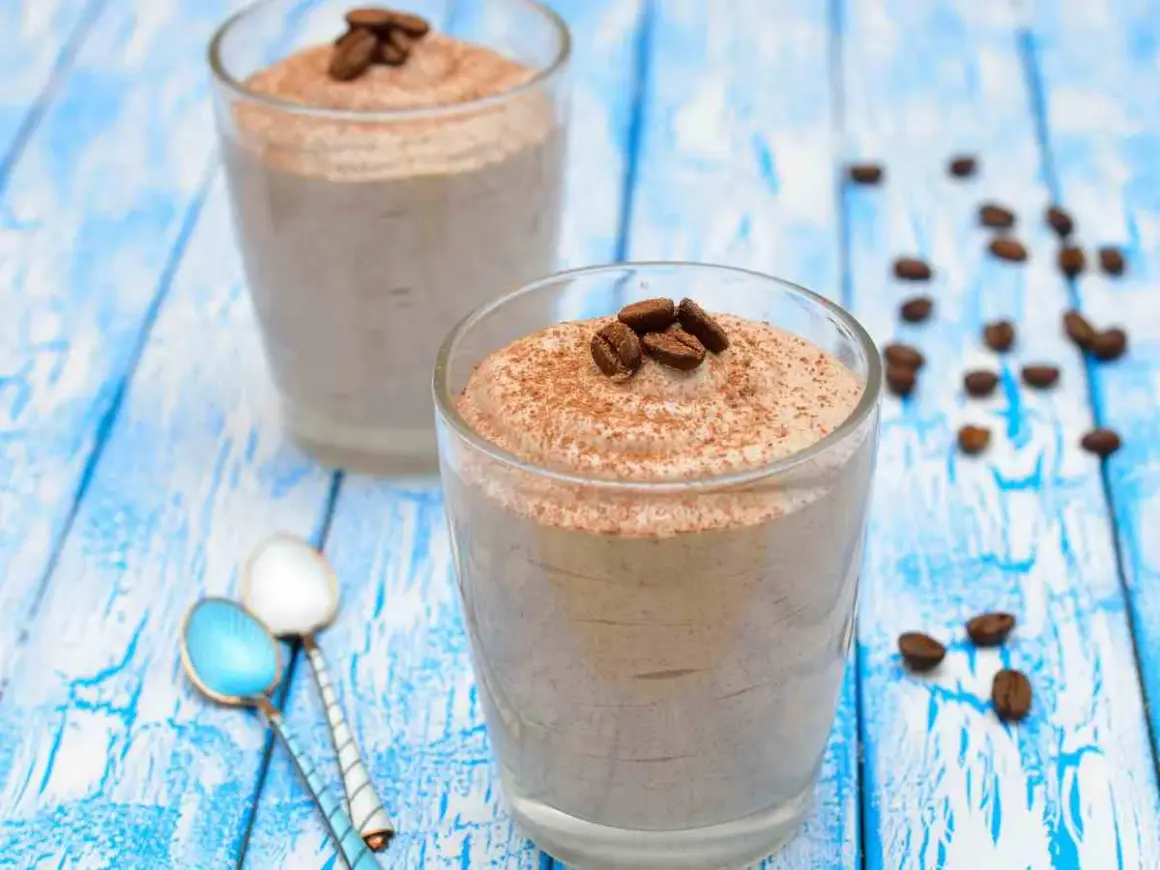 Delizioso sorbetto al caffè ricetta, guarnito con chicchi di caffè e cacao, servito in bicchieri su un tavolo di legno blu.