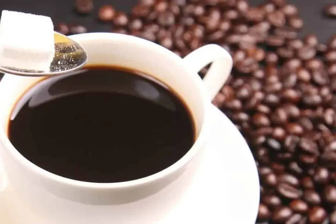 Tazza di caffè decaffeinato, chicchi tostati e zolletta di zucchero su cucchiaino. Ideale per chi vuole godersi il gusto senza preoccuparsi della pressione.