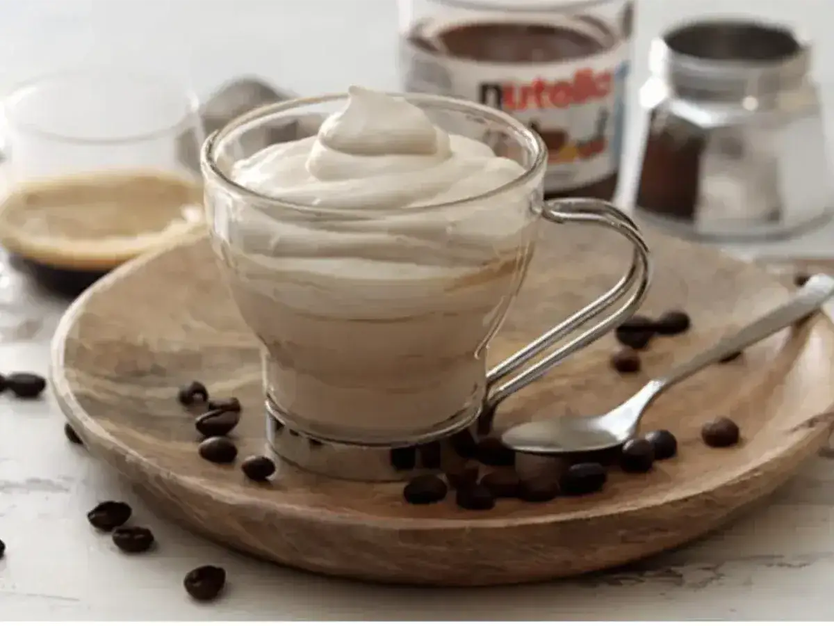 Un delizioso espressino freddo pugliese, cremoso e invitante, servito su un vassoio di legno con chicchi di caffè.
