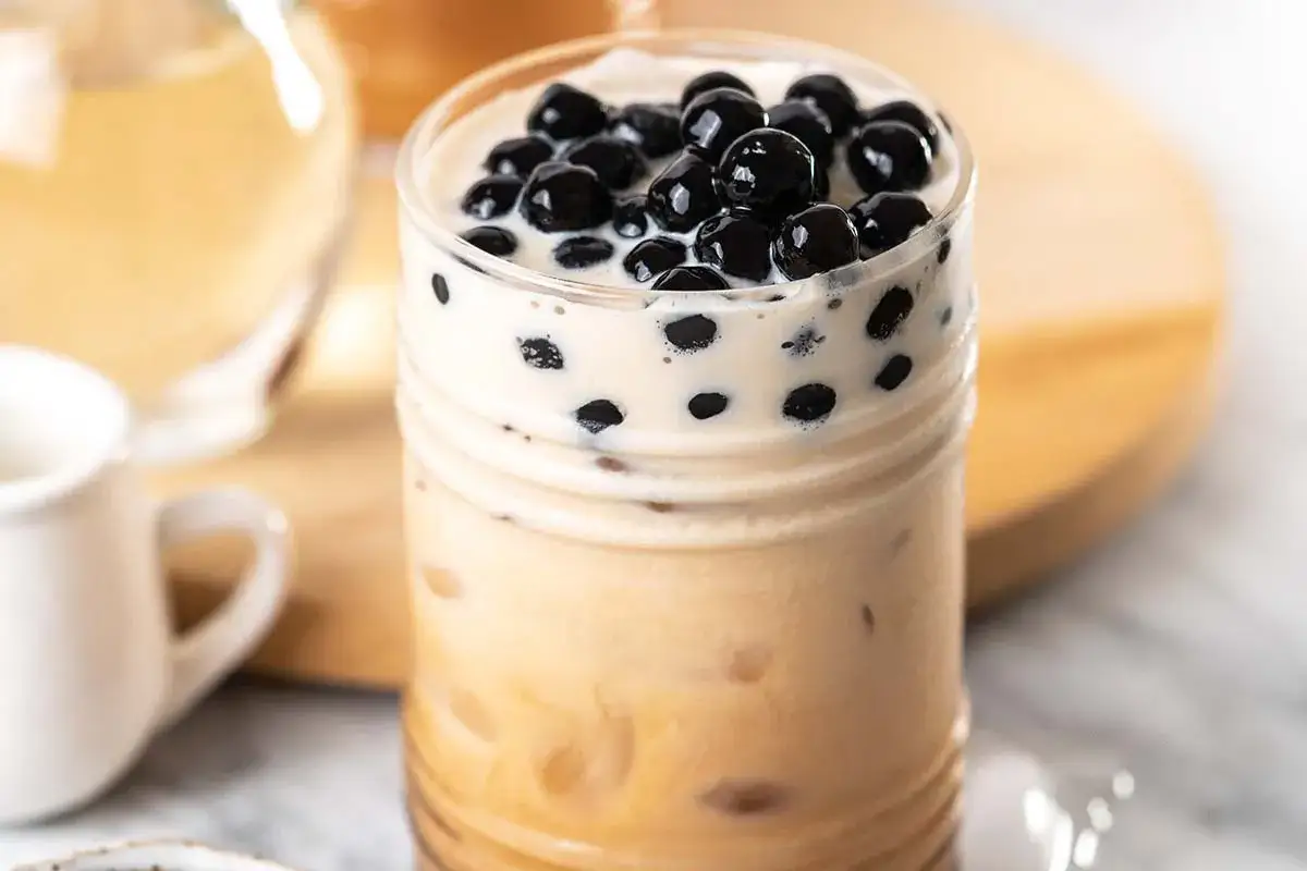 Un delizioso bubble tea tapioca con perle nere galleggianti in una schiuma cremosa.