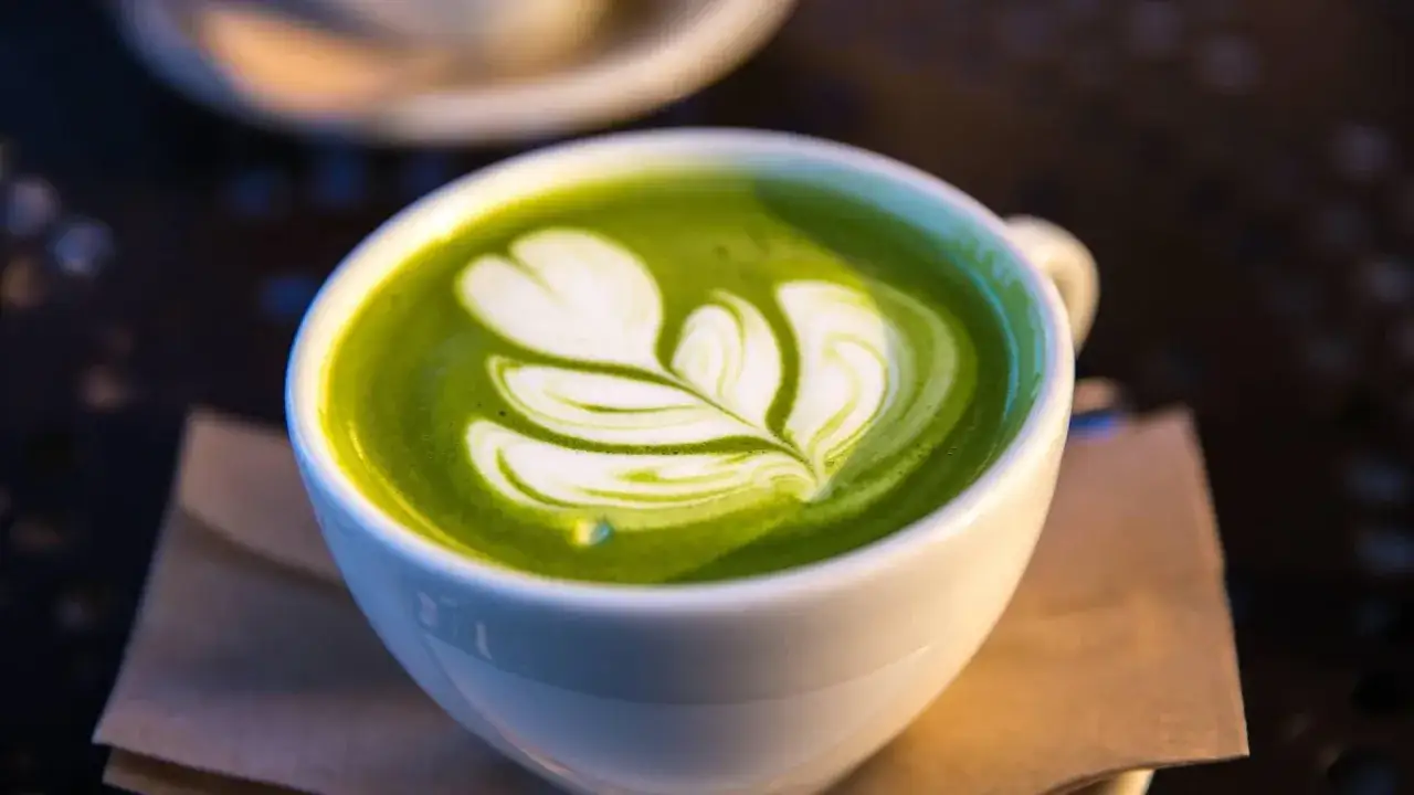 Un cremoso cappuccino matcha con schiuma latte decorata a forma di foglia.