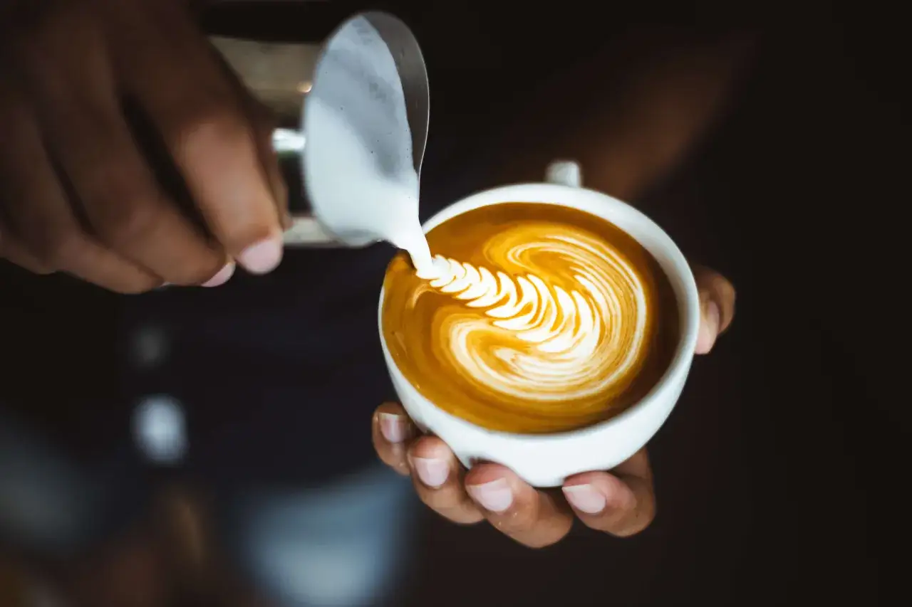 Barista crea disegni sul cappuccino con latte montato. Un'arte che trasforma il caffè in un'opera d'arte.