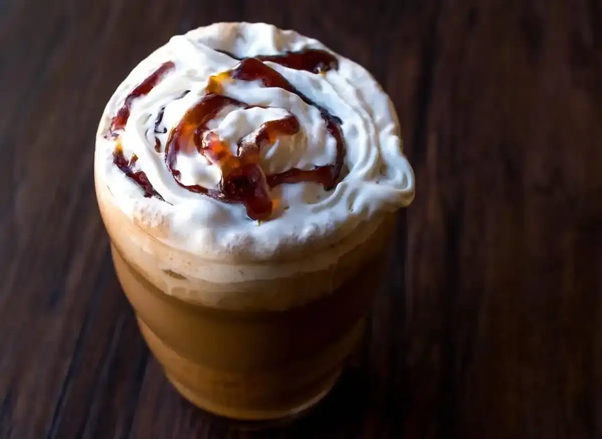 Frappuccino ricetta: un bicchiere di caffè freddo con panna montata e sciroppo al caramello, perfetto per una pausa golosa.