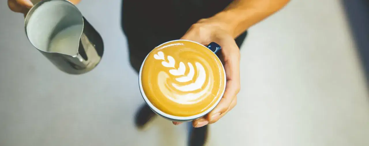 Latte art a forma di tulipano, con schiuma di latte che crea petali bianchi su un caffè cremoso.