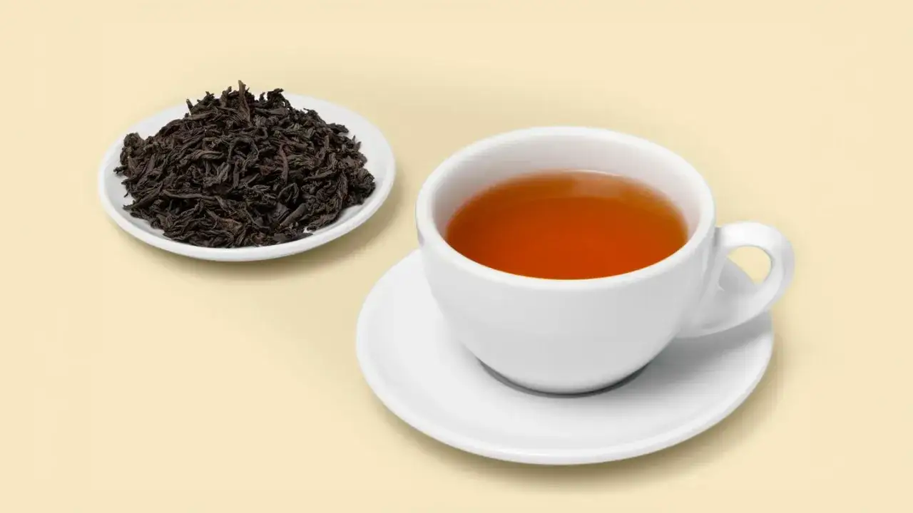Tè nero in tazza e su piattino, con foglie secche a lato. Un alleato per chi cerca un aiuto naturale: il tè nero fa dimagrire.