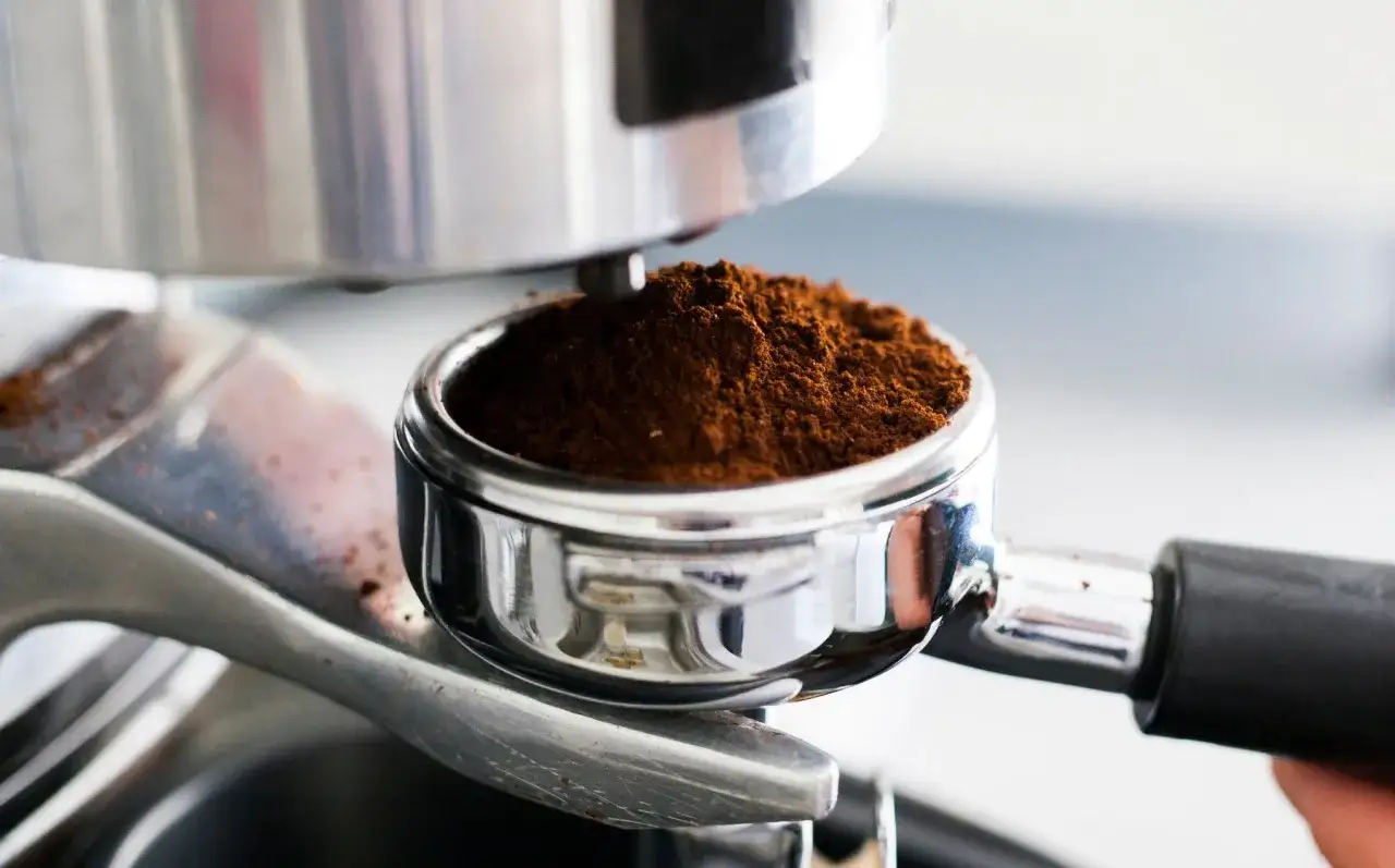 Portafiltro pieno di caff&egrave; macinato pi&ugrave; fine, pronto per un espresso perfetto.