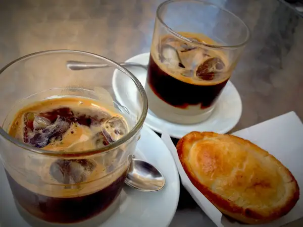 Due caffè salentino con ghiaccio e una pastarella su un tavolino.