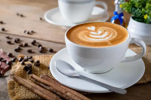 Tazza di cappuccino con latte art, chicchi di caffè e cannella. Nonostante la sua bellezza, la schiuma del cappuccino fa male se consumata in eccesso.