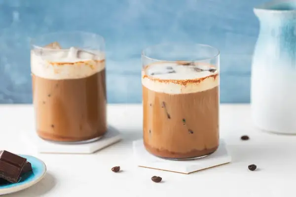 Due bicchieri di caffè freddo con schiuma e cacao, perfetti per una ricetta estiva.