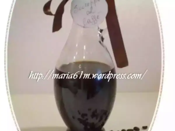 Caraffa di sciroppo al caffè fatto in casa, con etichetta scritta a mano e chicchi di caffè sparsi.