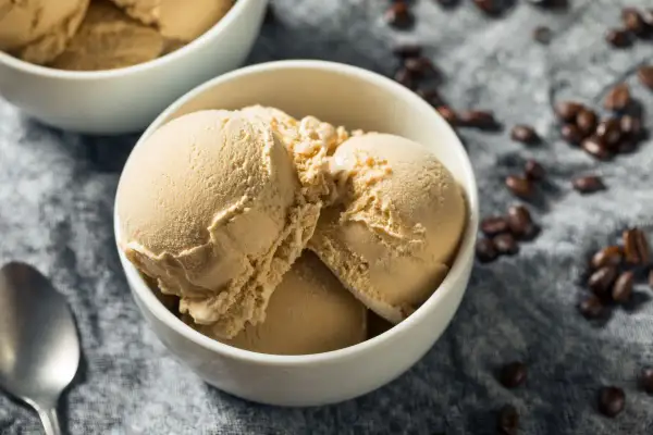 Coppetta di gelato al caffè senza gelatiera e senza latte condensato, con chicchi di caffè sparsi.