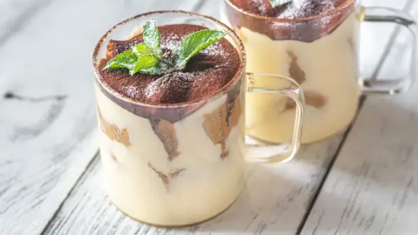 Delizioso monoporzione tiramisù in bicchiere, guarnito con cacao e menta fresca.