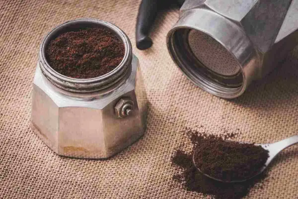 Il filtro moka incastrato è pronto per un caffè aromatico. Caffè macinato fine su tela di juta.