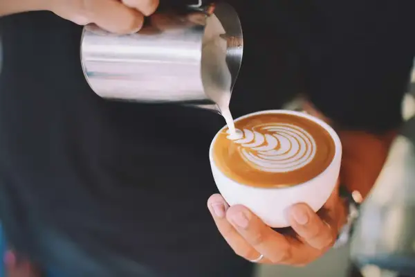 Latte art su un caffè, mostrando la differenza tra caffelatte e cappuccino con schiuma di latte versata.