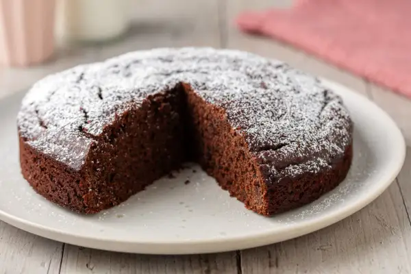 Una deliziosa torta caffè e cioccolato fondente, cosparsa di zucchero a velo, con una fetta mancante.
